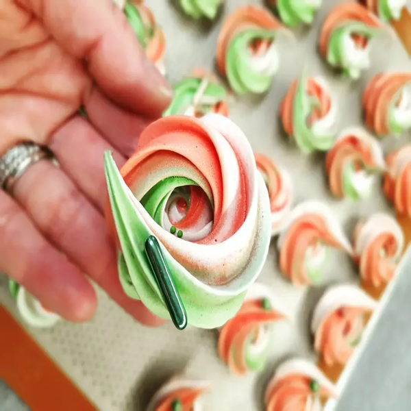 Image de meringues oranges, vertes et blanches avec des perles sucrées sur le dessus confectionnées par Le Fouet Enchanté.