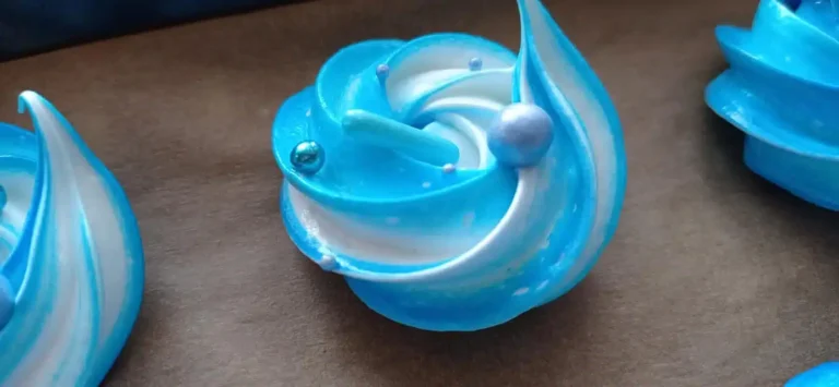 Image de meringues bleues et blanches avec des perles sucrées sur le dessus confectionnées par Le Fouet Enchanté.